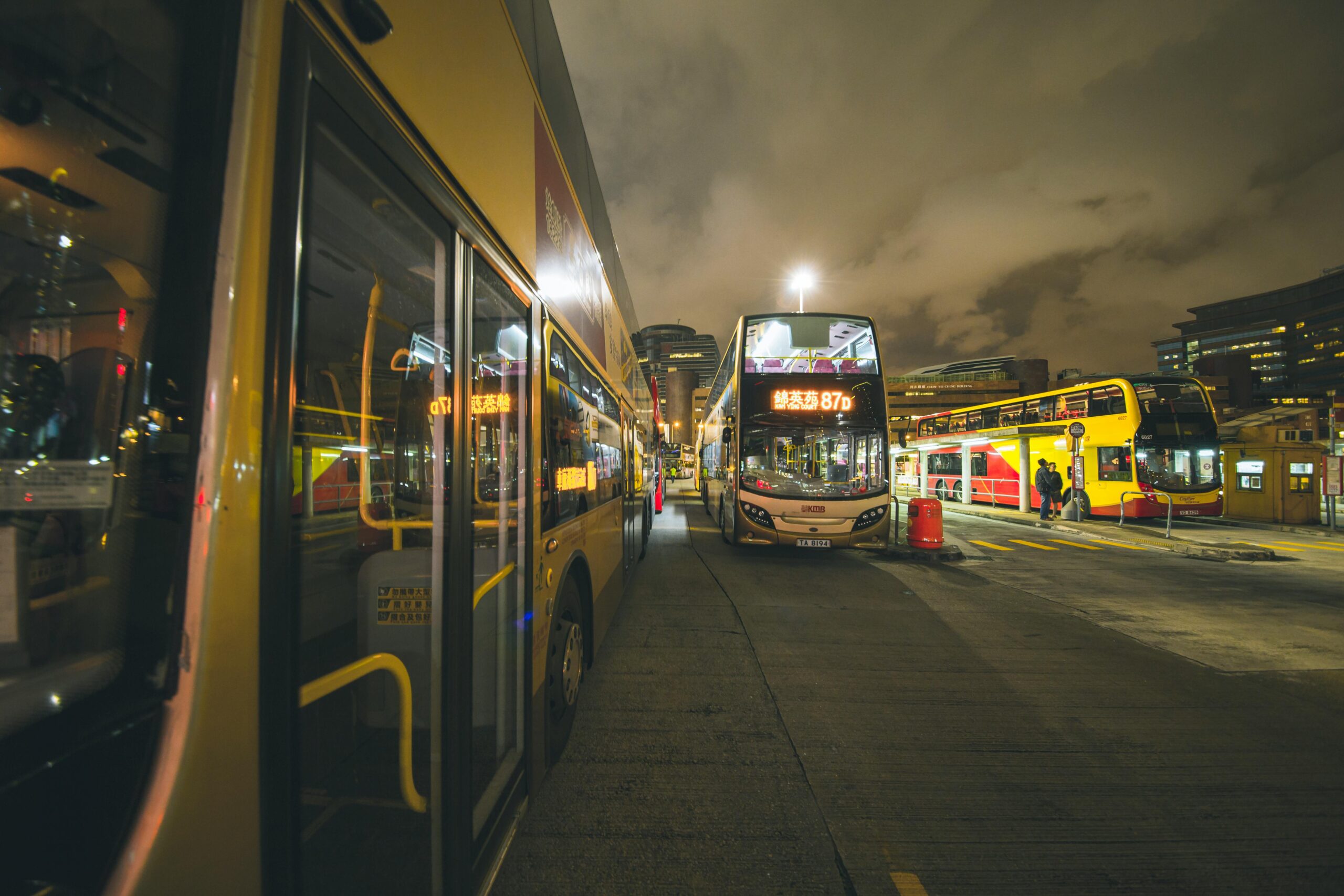 How to Stop Motion Sickness Bus: My Battle-Tested Playbook from 20+ Years of NYC Gridlock and Beyond 2 City buses at a bustling nighttime bus stop in Kowloon, showcasing urban public transportation.