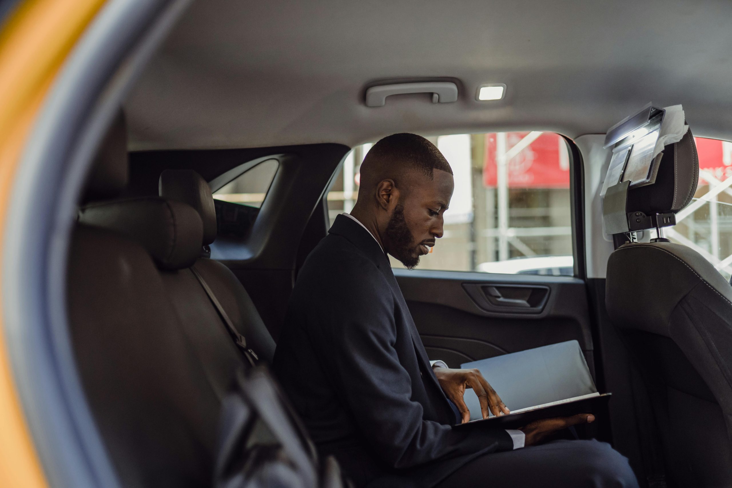LGA Shuttle Reviews 2026: 5 Honest Findings for Corporate Groups 2 A professional man in a suit reads documents while sitting in a car interior, conveying a business theme.