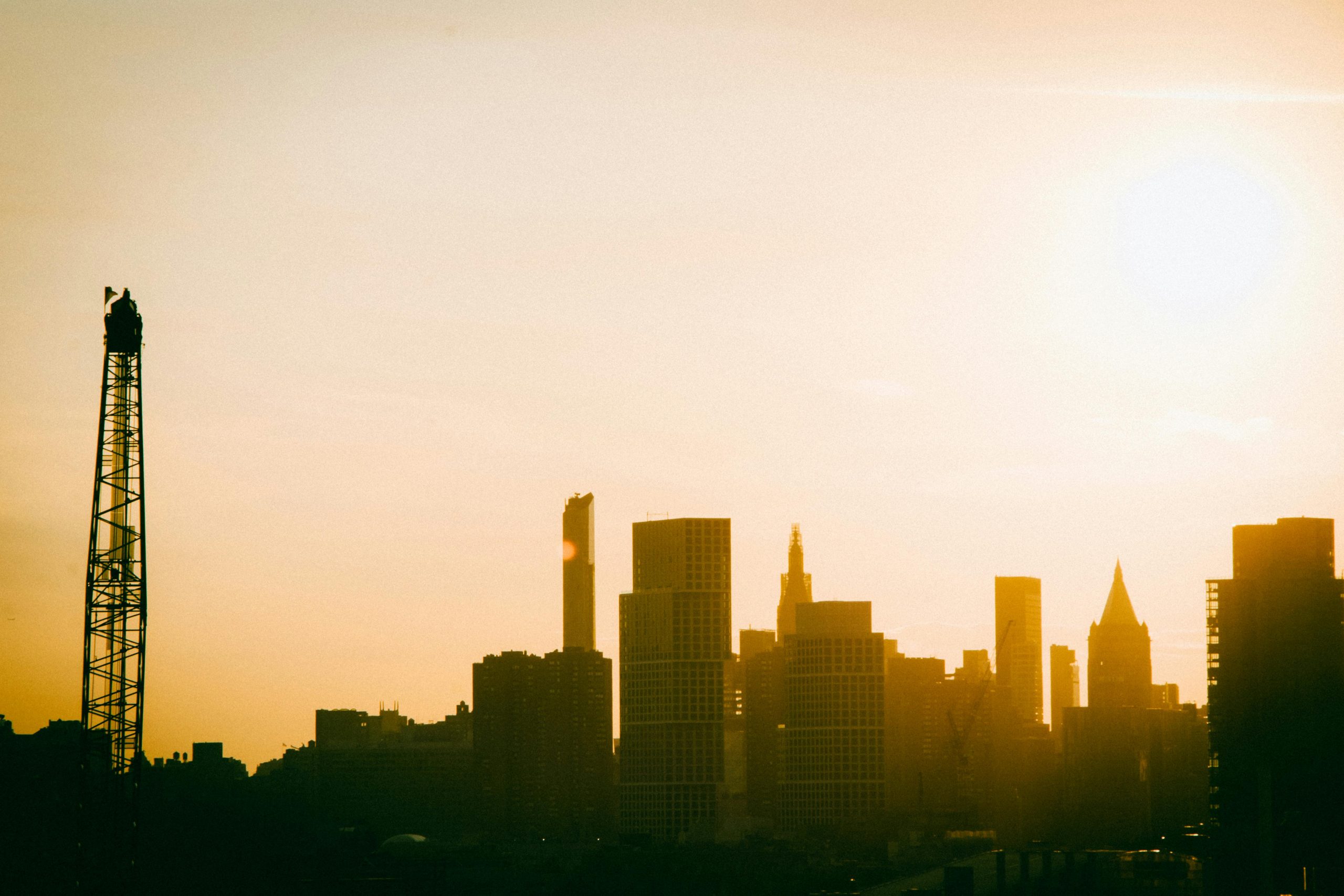 Silhouette of the New York City skyline at sunrise, showcasing a warm and golden urban landscape.