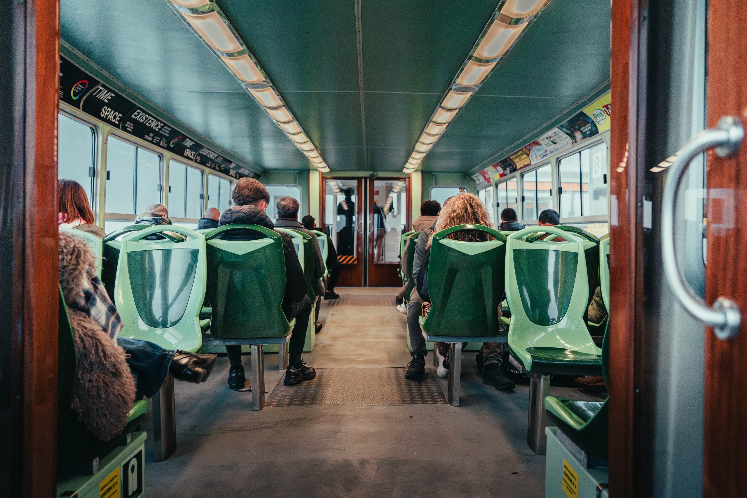 Passengers seated inside a Venetian vaporetto waterbus, captured from the interior view.