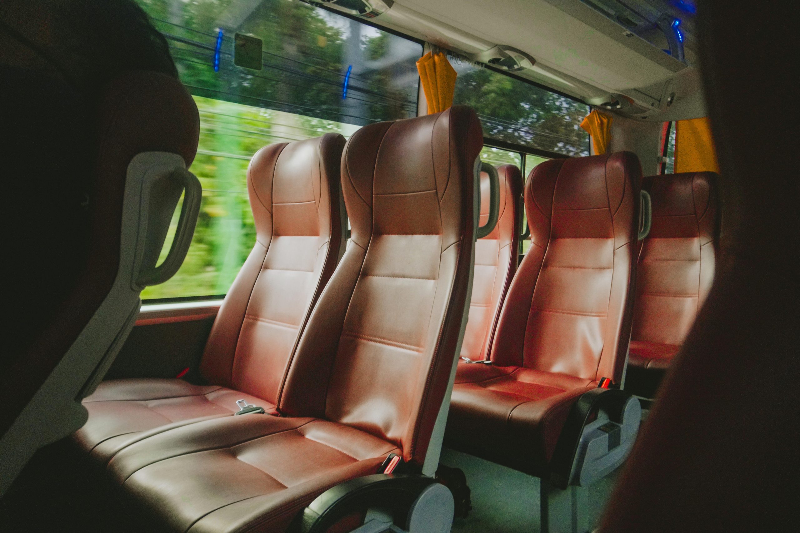 Interior view of a luxurious bus with empty red leather seats, offering comfort and style.