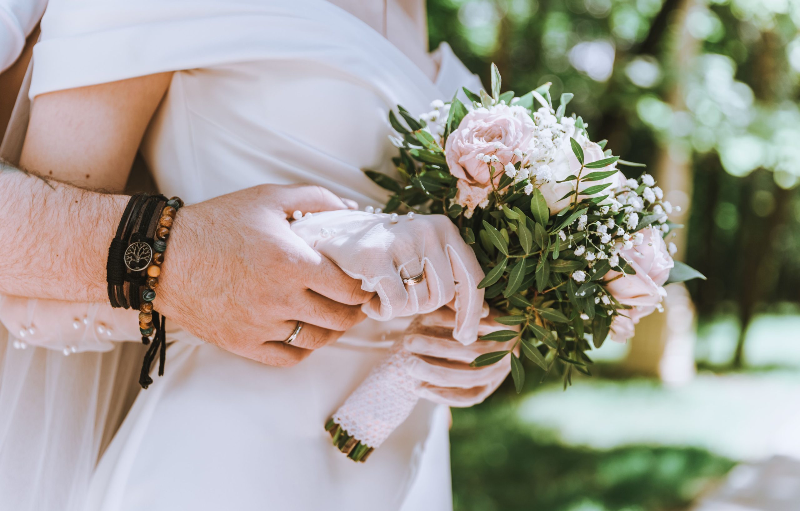 Close-up of a bride and groom holding a floral bouquet, symbolizing love and marriage.