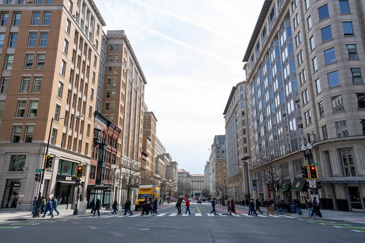 NYC to DC Transportation Tips: 7 Honest 2026 Cost Numbers 2 Downtown Washington DC road with high-rise buildings and pedestrians crossing.