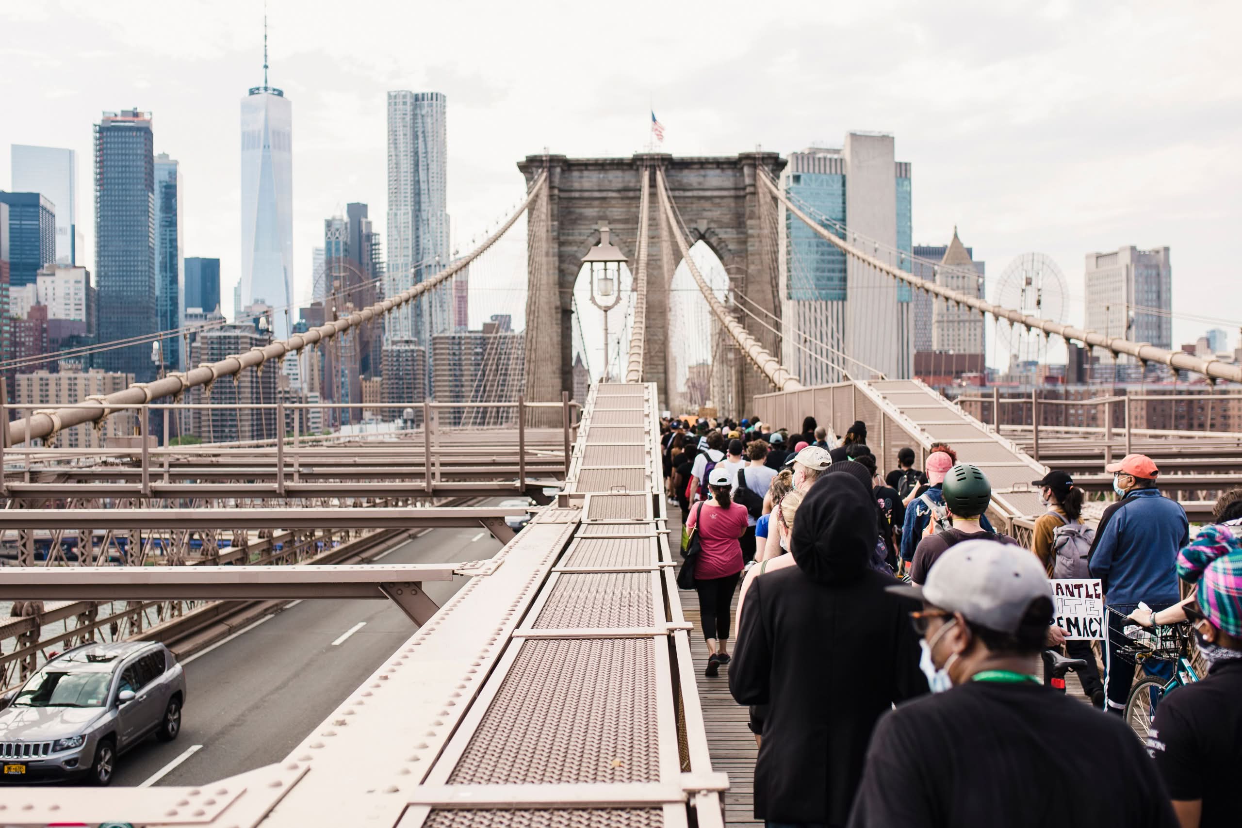 Charter Buses NYC for Groups: A No-Nonsense 2026 Guide from Someone Who's Been Stuck in Midtown Traffic Too Many Times 2 Crowd marching on Brooklyn Bridge for justice and solidarity protest.