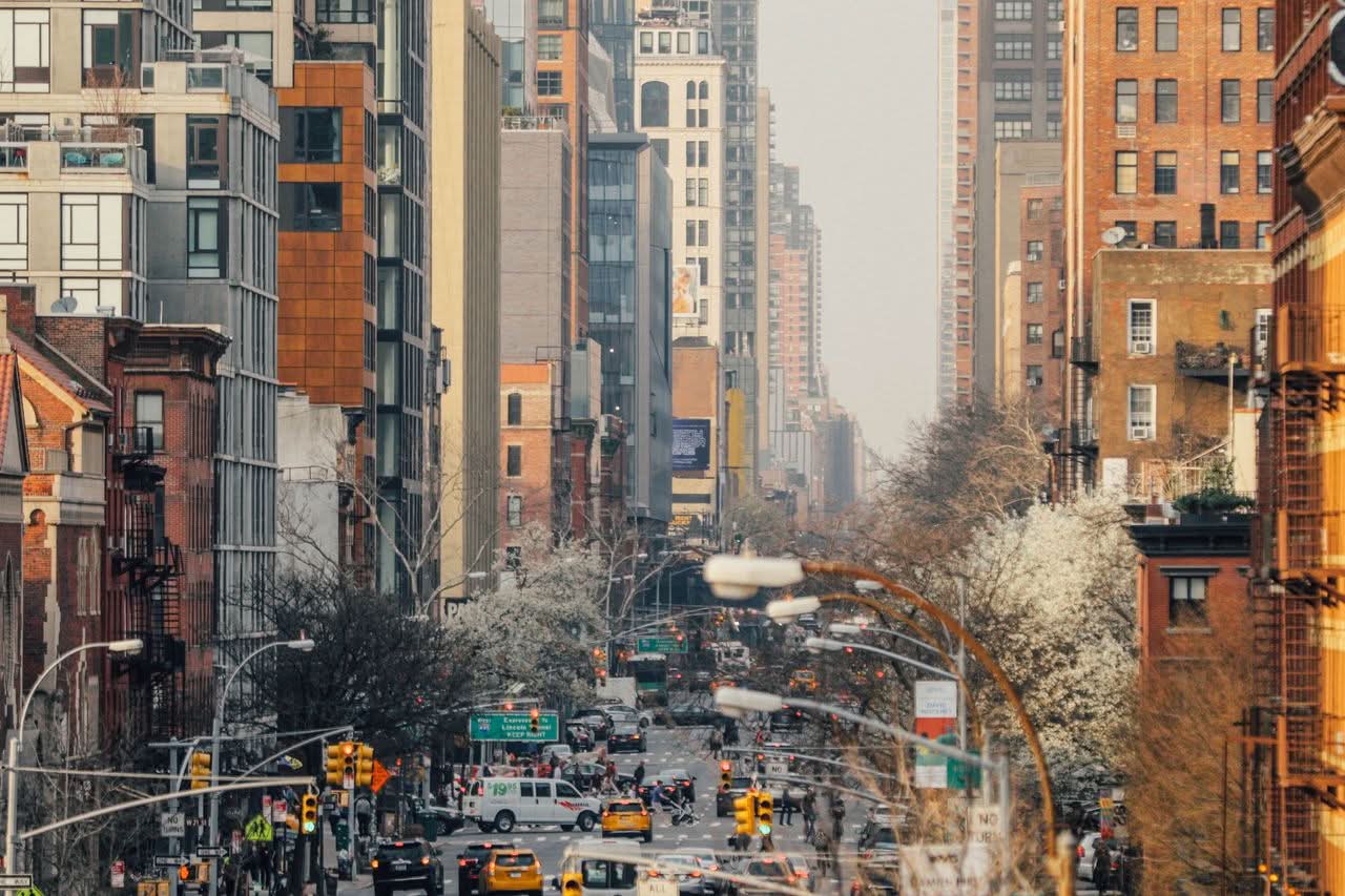 How Much Is a Minibus in NYC? Honest 2026 Group Prices 4 Bustling street view in New York City with high-rise buildings and spring foliage.